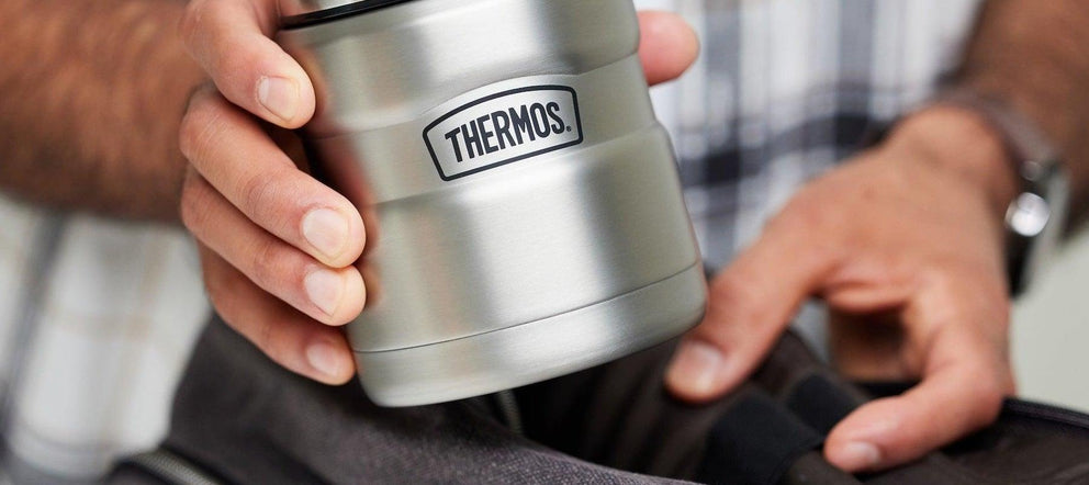 Thermos yemek termosunu çantasına koyan çalışan veya öğrenci